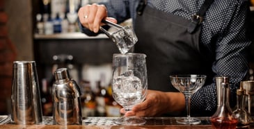 Bartender placing ice in glass using tongs