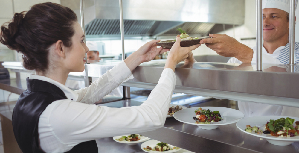 Chef passing plate of food to server