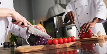 chefs cutting vegetables on cutting board