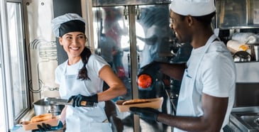 Man and woman serving food from a food truck