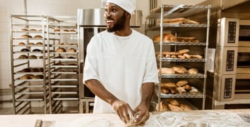 Baker working with dough in a commercial bakery kitchen