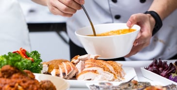 Chef spooning sauce onto slices of turkey