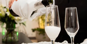 Server pouring champagne into a glass flute