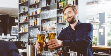 Bartender extending two glasses of beer.
